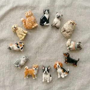 Detailansicht verschiedener Keramik-Katzen- und Hundeanhänger auf Leinenstoff.
