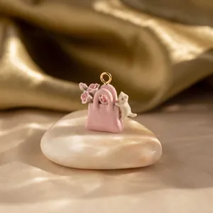 Primo piano di un ciondolo a forma di borsa rosa con un gattino bianco e delle rose