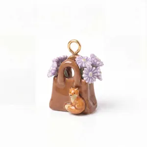 Dettaglio di un ciondolo a borsa in ceramica marrone con fiori viola e una volpe.