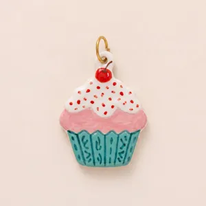 Detalle de un amuleto de cupcake colorido con glaseado rosa y cereza roja encima