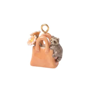 Dettaglio di un tenero procione in porcellana che si arrampica su un ciondolo a borsa.