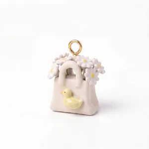 Primo piano di un ciondolo borsa in ceramica con anatroccolo giallo e margherite