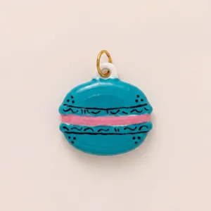 Primer plano de un colgante de macaron en esmalte azul con relleno rosa y aro dorado