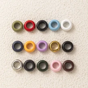 Perles donut colorées en acier inoxydable pour bijoux DIY sur fond blanc texturé