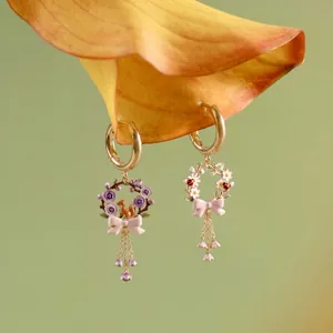 Detail view of asymmetric wreath earrings featuring an enamel squirrel and ladybug design