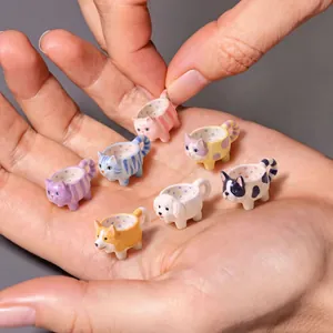 Detailed view of assorted miniature cartoon animal teacup charms held in a hand for scale.