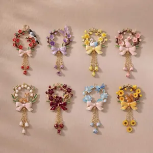 Detail view of colorful enamel floral wreath charms featuring animal motifs and tassels