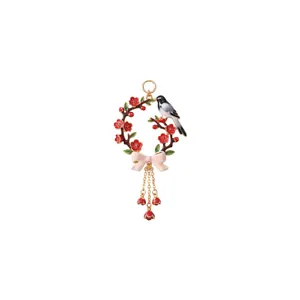 Detailed macro shot of an enamel bird and floral wreath pendant with bow decoration