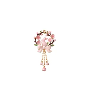 Macro view of pink enamel floral wreath pendant with dangling rabbit and flower charms