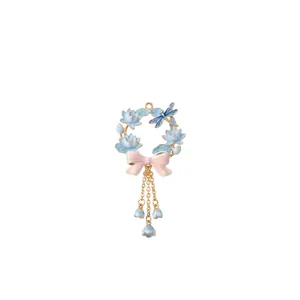 Detailed macro view of enamel flower wreath pendant with dragonfly and bow charms.