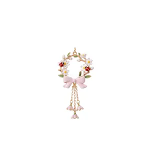 Detailed view of enamel flower wreath pendant with pink bow and ladybug charms