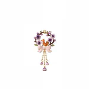 Detail shot of a whimsical floral wreath pendant featuring a small orange fox and pink bow.