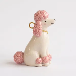 Detalle de un lindo colgante de caniche de cerámica rosa y blanco con anillo dorado.