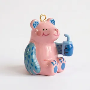 Vista detallada de un lindo colgante de oso rosa sosteniendo una taza azulada