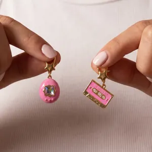 Detailed view of pink enamel Tamagotchi and cassette tape charms with gold star clasps