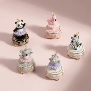Group of five hand-painted ceramic ballet animal pendants on a soft pink background