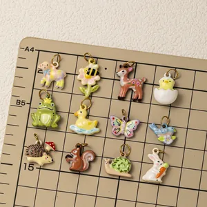 Variety of stainless steel animal charms for DIY jewelry on grid mat.