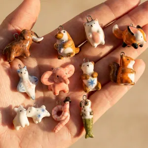 Gros plan de divers pendentifs animaux en céramique peints à la main sur une paume