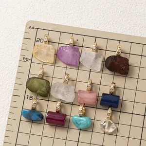 Détail macro de divers pendentifs en pierre naturelle sur un tapis de mesure quadrillé
