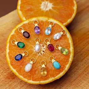 Pendentifs de pierre de naissance en forme de larme avec bordure dorée sur orange.