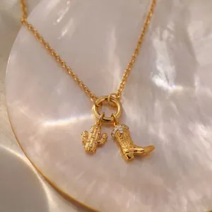 Nahaufnahme von goldenen Kaktus- und Cowboystiefel-Anhängern an einer Kette
