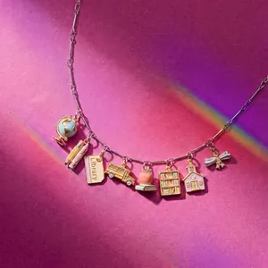 Detailed view of silver charm necklace with school-themed pendants on pink background