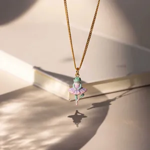 Detailed close-up of a cute ballerina frog pendant on a gold stainless steel chain.