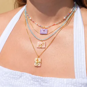 Detailed view of three layered necklaces with floral-themed envelope pendants.