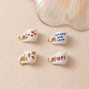 Detailed view of four mini cup charms featuring heart, flower and fruit patterns.