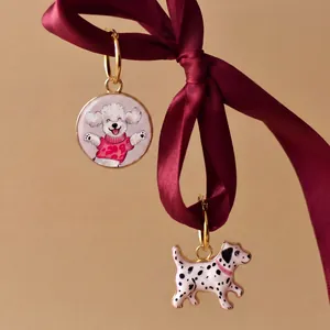 Detailaufnahme von vergoldeten Pudel- und Dalmatiner-Anhängern an einem eleganten Seidenband.