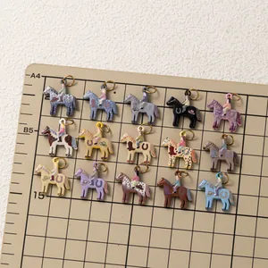 Close-up of colorful enamel horse pendants arranged on a measurement grid board.