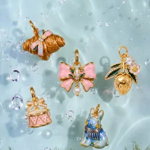 Detail of enamel rhinestone copper pendants featuring fruit, bow and rabbit designs in water.