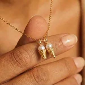 Detailed macro close-up of gold ice cream cone charms with pearls on a dainty chain