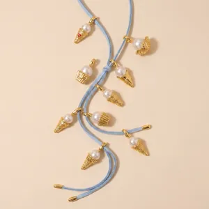 Charming gold ice cream pearl pendants on a light blue cord necklace detail view