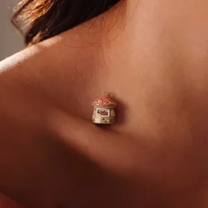 Detail shot of a miniature fairy tale mushroom house pendant on skin texture.