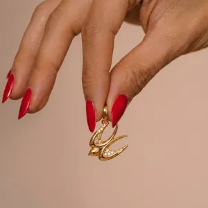 Détail d'un luxueux pendentif hirondelle en or avec des accents de cristaux brillants.