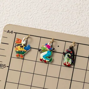 Detailed view of colorful enamel animal charms for DIY jewelry making on grid mat