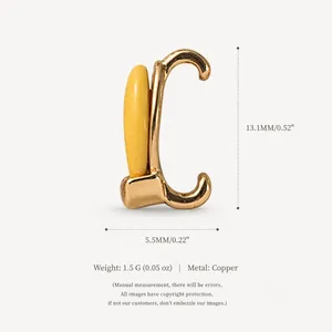 Detailed view of a gold-colored copper shoe charm with yellow paint and size measurements