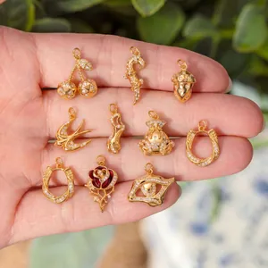 Vue détaillée de divers charms en acier titane doré avec des pierres zircones