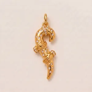 Détail macro d'un pendentif en acier titane doré avec mains serrées et pierres incrustées