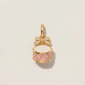 Detailed close-up of a 14K gold-plated drum charm with pink enamel and diamond bow