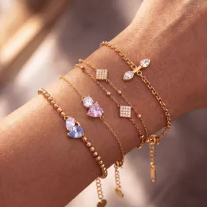 Close-up of four layered gold-plated titanium steel bracelets with colorful zircons.
