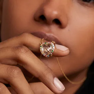 Dettaglio collana con medaglione a cuore d'oro con pietre colorate e motivo colomba.