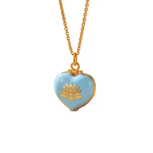 Detail view of a light blue enamel heart locket necklace with a golden lotus flower