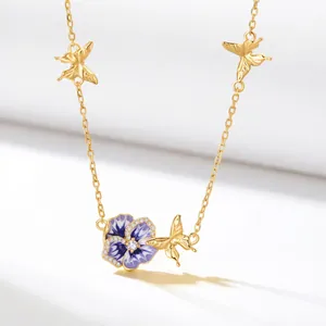 Close-up of gold butterfly and purple pansy birth flower enamel necklace