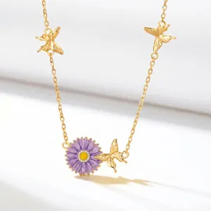 Close-up of gold copper necklace featuring purple daisy pendant and butterfly charms