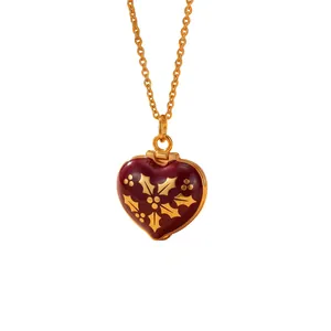 Close-up detail of burgundy enamel heart locket necklace with gold floral motifs