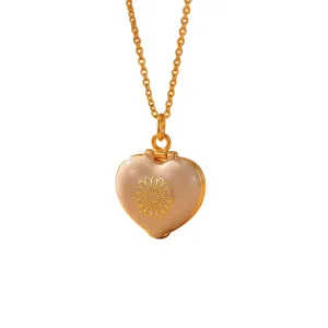 Detail view of heart-shaped gold enamel locket necklace with daisy pattern engraving
