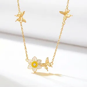 Close-up of golden birth flower necklace with white enamel petals and butterflies
