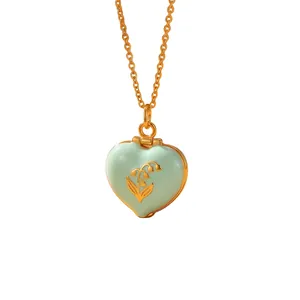 Detailed view of mint green enamel heart locket with golden lily of the valley engraving